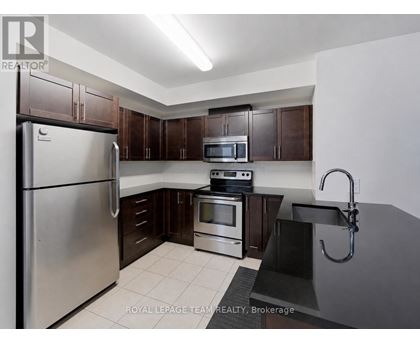A kitchen with a refrigerator, microwave, oven, and sink.