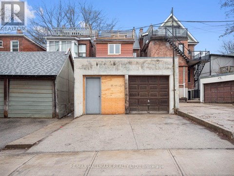 A building with a grey garage door and a brown door is for sale.