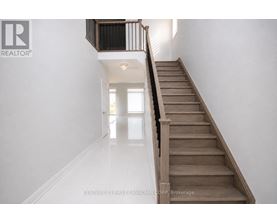 A staircase with a black railing and wooden steps leading to a bright room.
