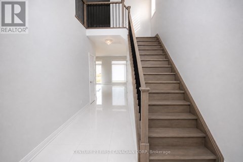 A staircase with a black railing and wooden steps leading to a bright room.