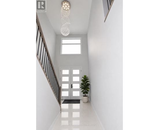 A white hallway with a plant and a chandelier.