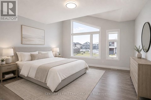 A bedroom with a large bed, a nightstand with a lamp, and a view of the outdoors through a window.