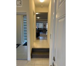 A hallway with a door on the right and a window with blinds on the left.