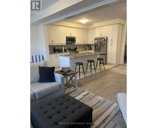 A modern kitchen with a bar stool and a black ottoman.