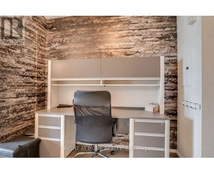 A room with a stone wall and a desk with a chair.