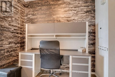 A room with a stone wall and a desk with a chair.