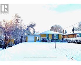 A house with a snowy front yard and trees in the background.