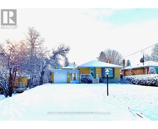 A house with a snowy front yard and trees in the background.