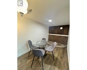 A dining room with a glass table and grey chairs.