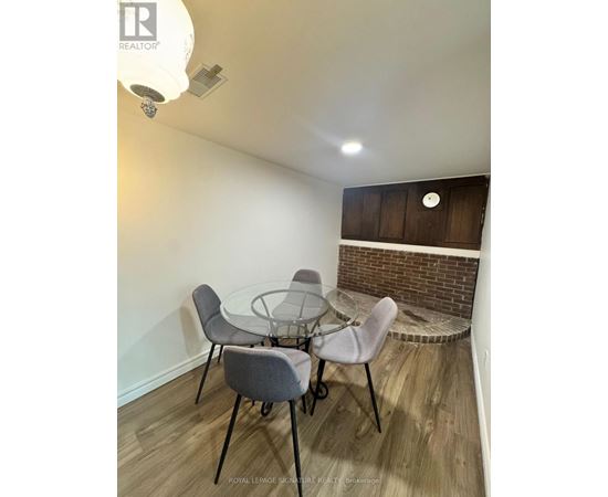 A dining room with a glass table and grey chairs.