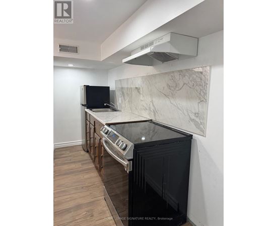A kitchen with a black oven and a marble backsplash.