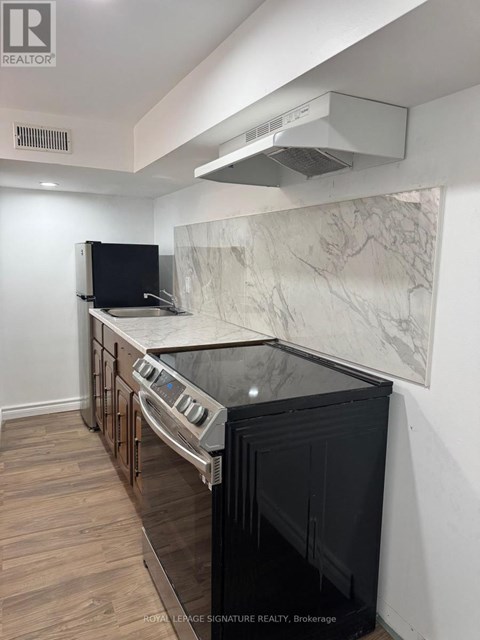A kitchen with a black oven and a marble backsplash.