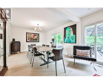 A dining room with a table set for six and a painting on the wall.