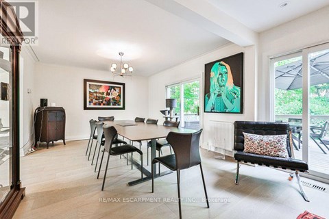 A dining room with a table set for six and a painting on the wall.