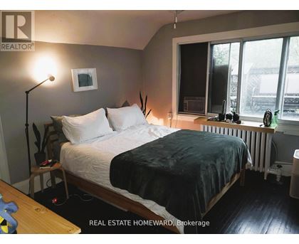 A bedroom with a bed, nightstand, and window.