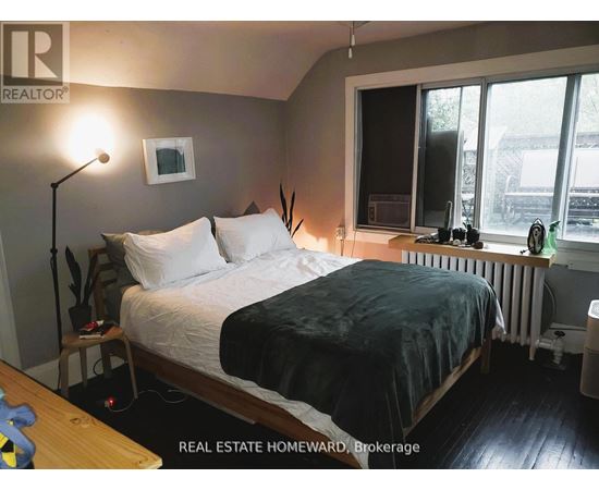 A bedroom with a bed, nightstand, and window.
