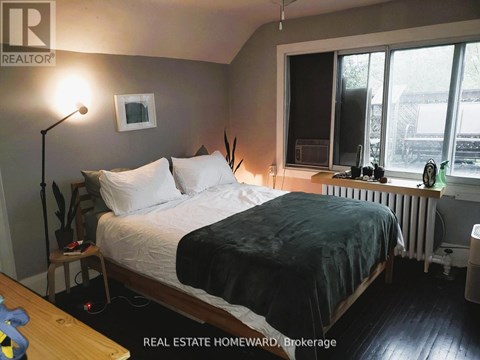 A bedroom with a bed, nightstand, and window.