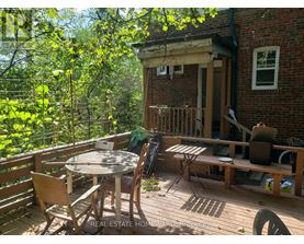 A wooden deck with a table and chairs is surrounded by trees.