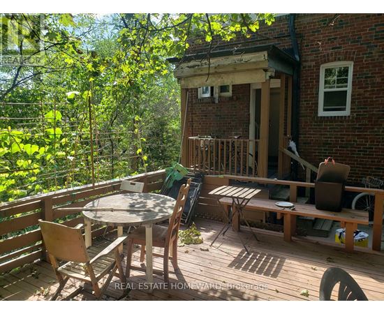 A wooden deck with a table and chairs is surrounded by trees.