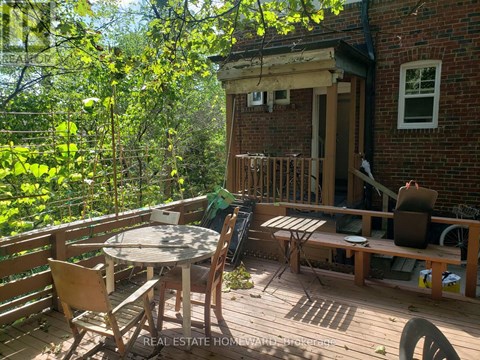 A wooden deck with a table and chairs is surrounded by trees.