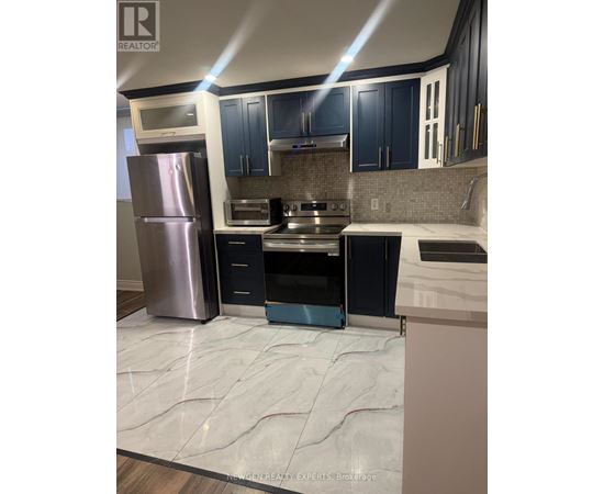 A kitchen with a refrigerator, oven, and microwave.