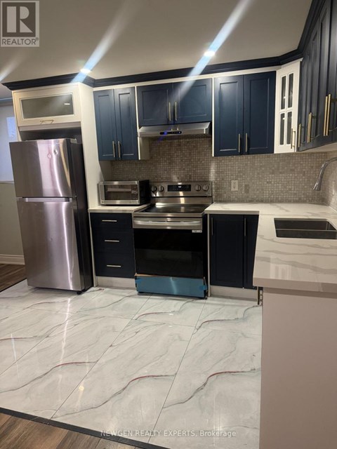 A kitchen with a refrigerator, oven, and microwave.