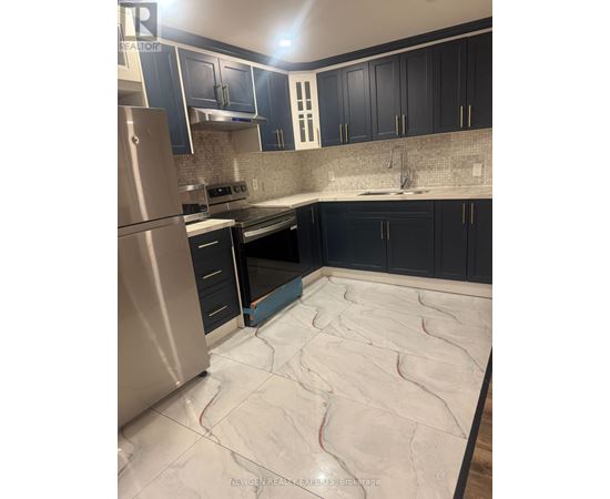 A kitchen with a stainless steel refrigerator and black cabinets.