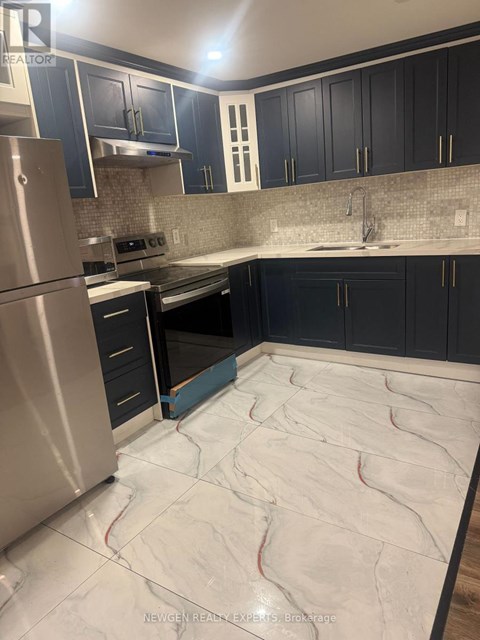 A kitchen with a stainless steel refrigerator and black cabinets.