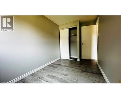 A room with a wooden floor and a door leading to another room.