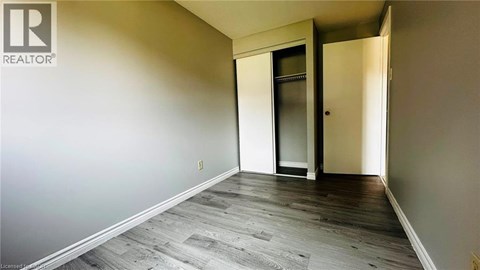 A room with a wooden floor and a door leading to another room.