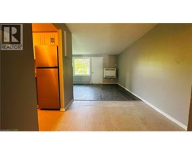 A room with a refrigerator and a door leading to another room.