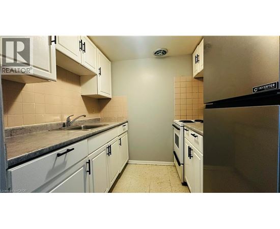 A kitchen with white cabinets and a black fridge.