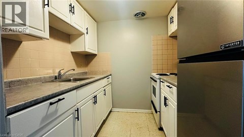 A kitchen with white cabinets and a black fridge.