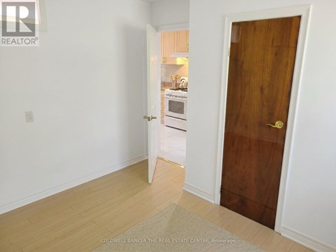 A room with a wooden door and a white wall.