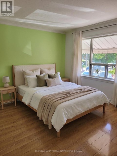 A bedroom with a bed, nightstand, and window.