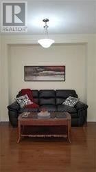 A black leather couch with pillows and a coffee table in front of a painting.
