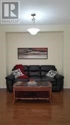 A black leather couch with pillows and a coffee table in front of a painting.