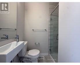 A white sink and toilet in a bathroom with a glass shower door.