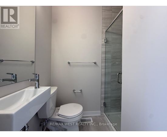 A white sink and toilet in a bathroom with a glass shower door.