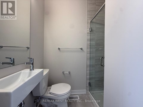 A white sink and toilet in a bathroom with a glass shower door.