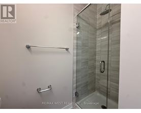 A glass shower stall with a glass door and a silver grab bar.
