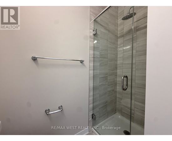 A glass shower stall with a glass door and a silver grab bar.