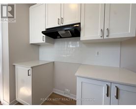 A kitchen with white cabinets and a black range hood.