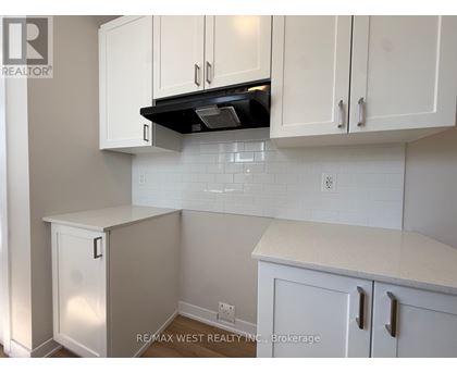 A kitchen with white cabinets and a black range hood.