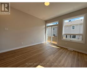 A room with wooden flooring and a window showing a view of a building.