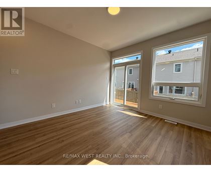 A room with wooden flooring and a window showing a view of a building.