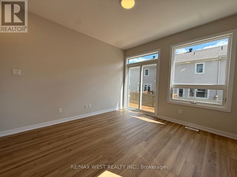 A room with wooden flooring and a window showing a view of a building.