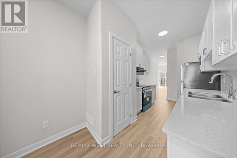 A white kitchen with a sink and a refrigerator.
