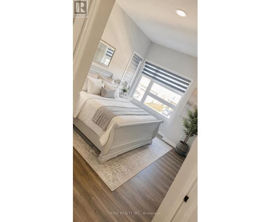 A bedroom with a large bed and a window with blinds.