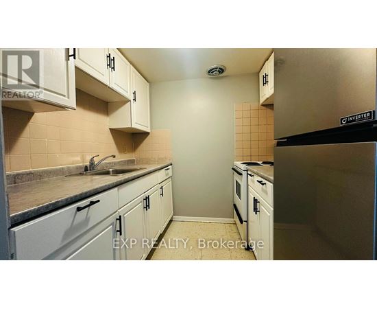 A kitchen with white cabinets and a black refrigerator.